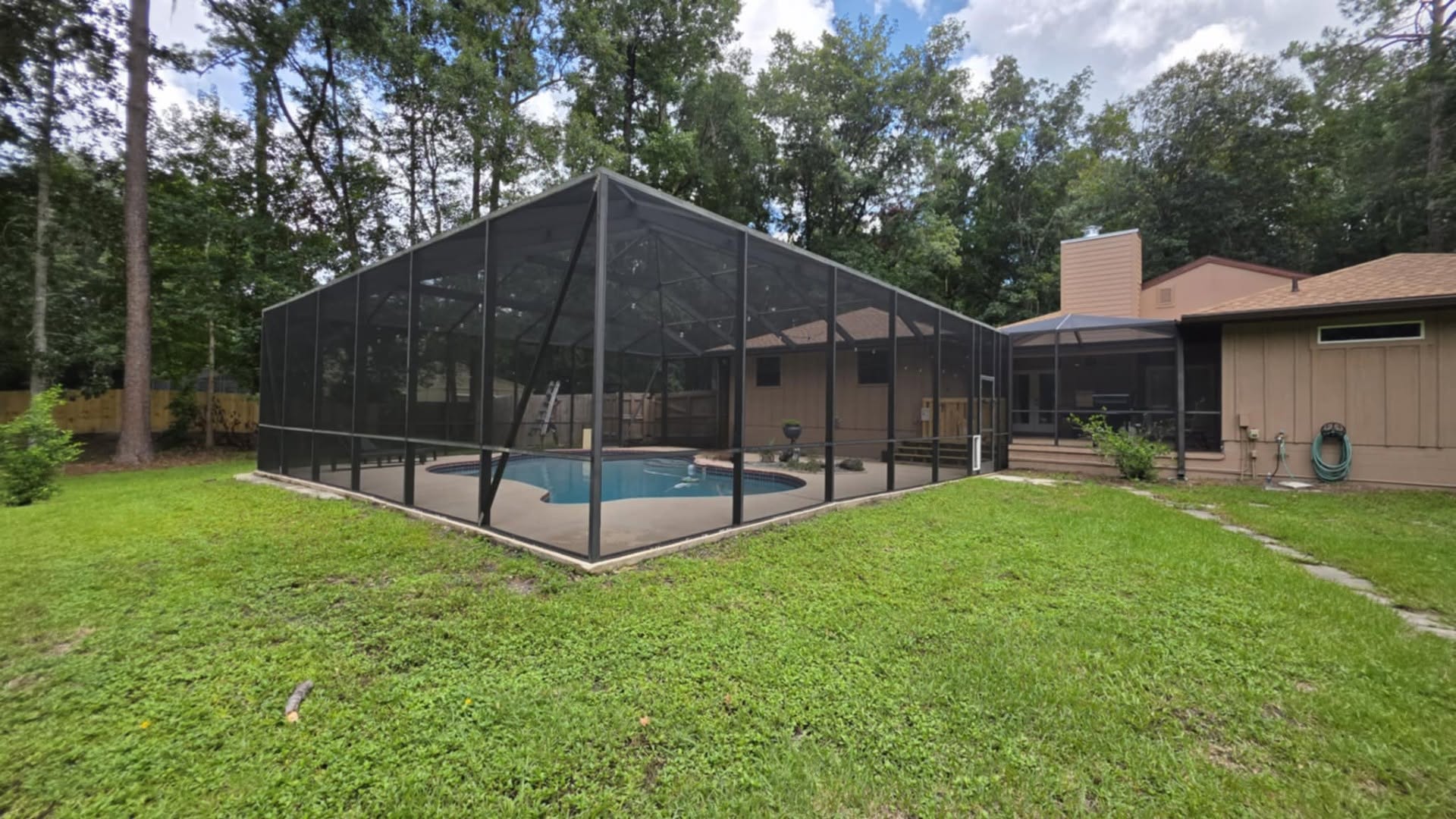 Large mansard pool enclosure beside a screened porch