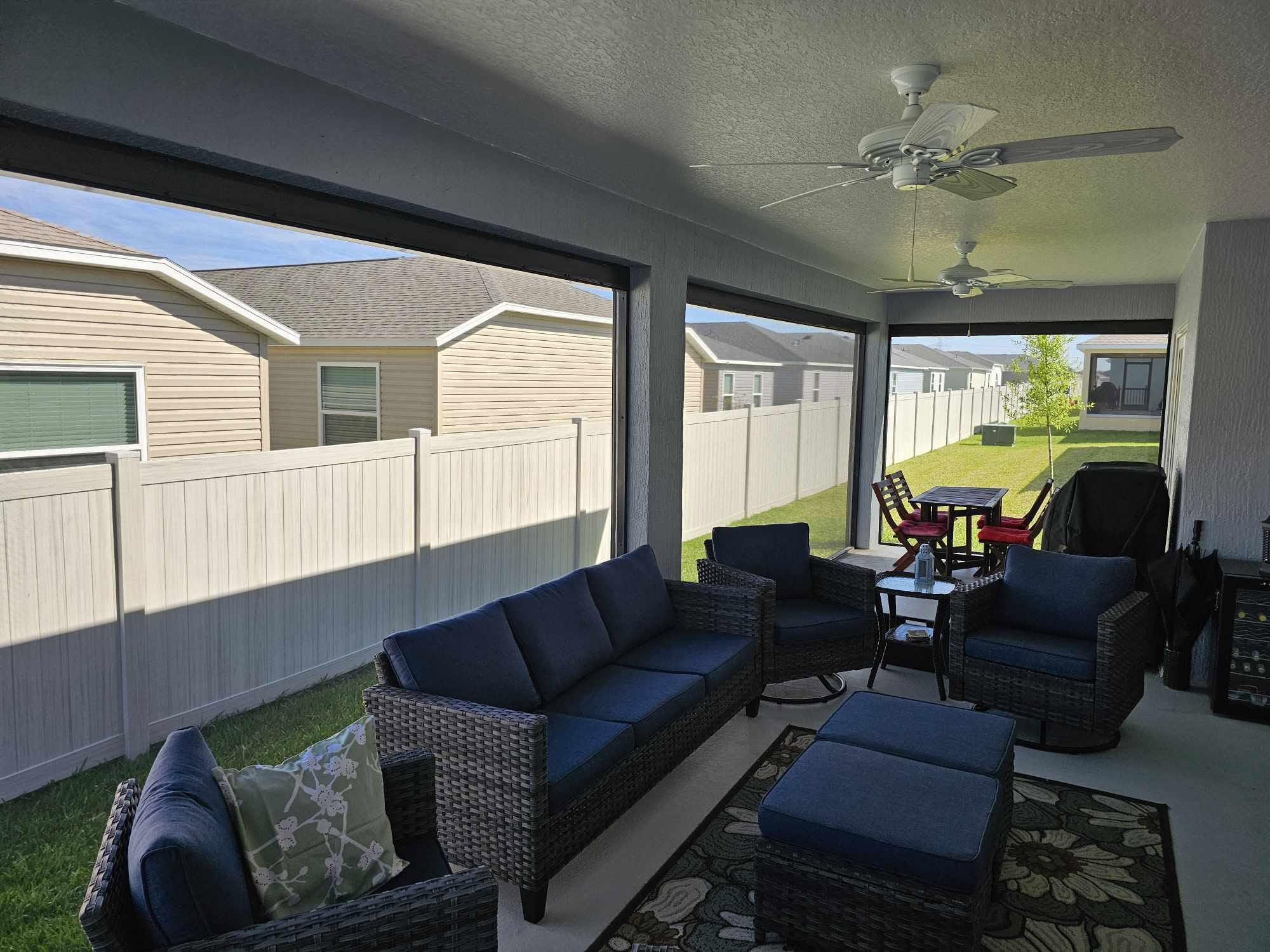 Covered screen room with lounge seating and ceiling fans