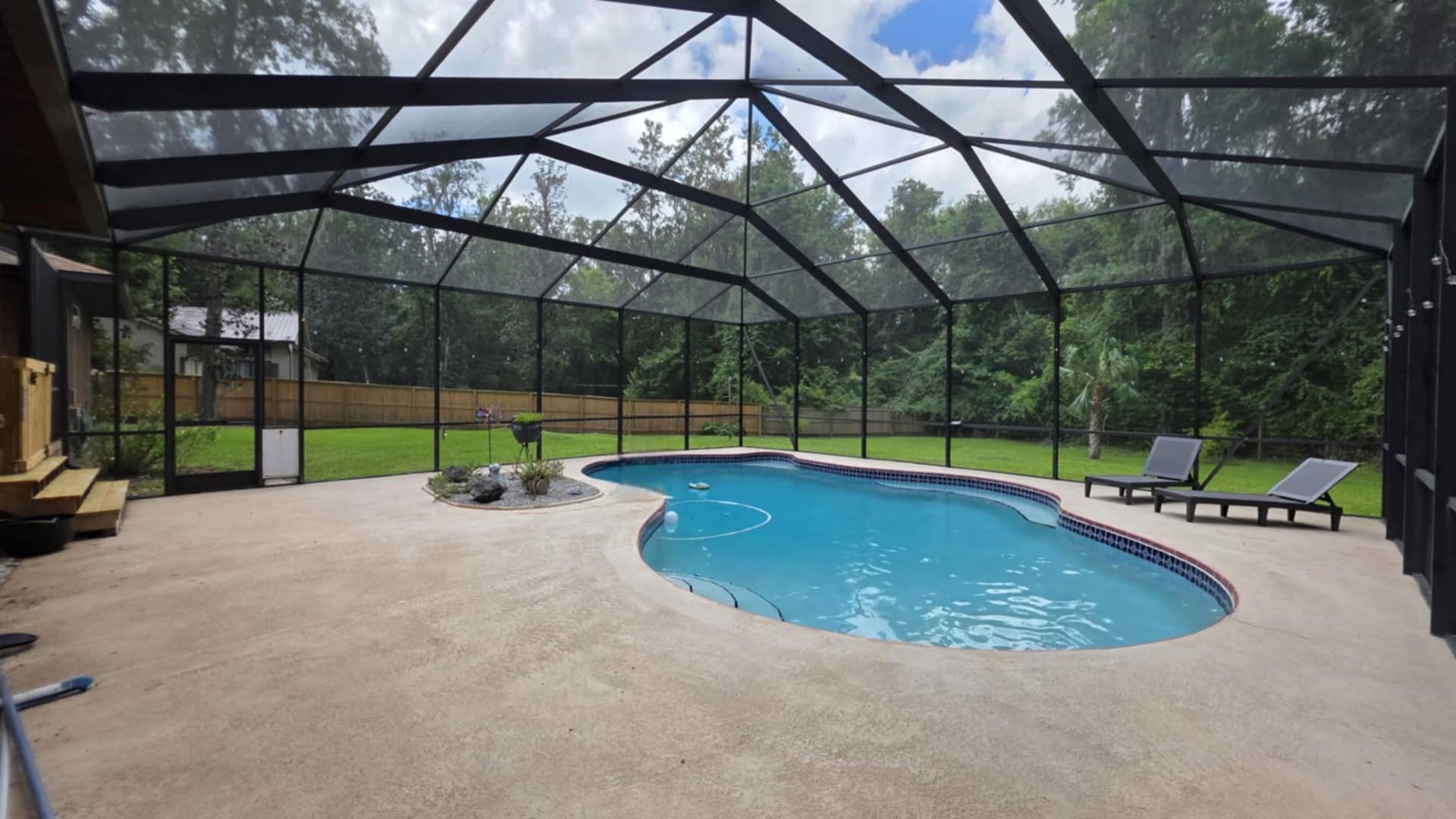 Screened pool enclosure surrounding a kidney-shaped pool